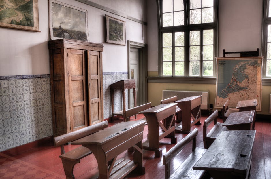 Old classroom with wooden benches and a map, evoking a vintage learning environment.