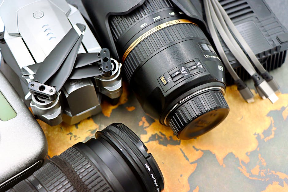 Top view of photography equipment including drone, camera lenses, and USB cables on map background.